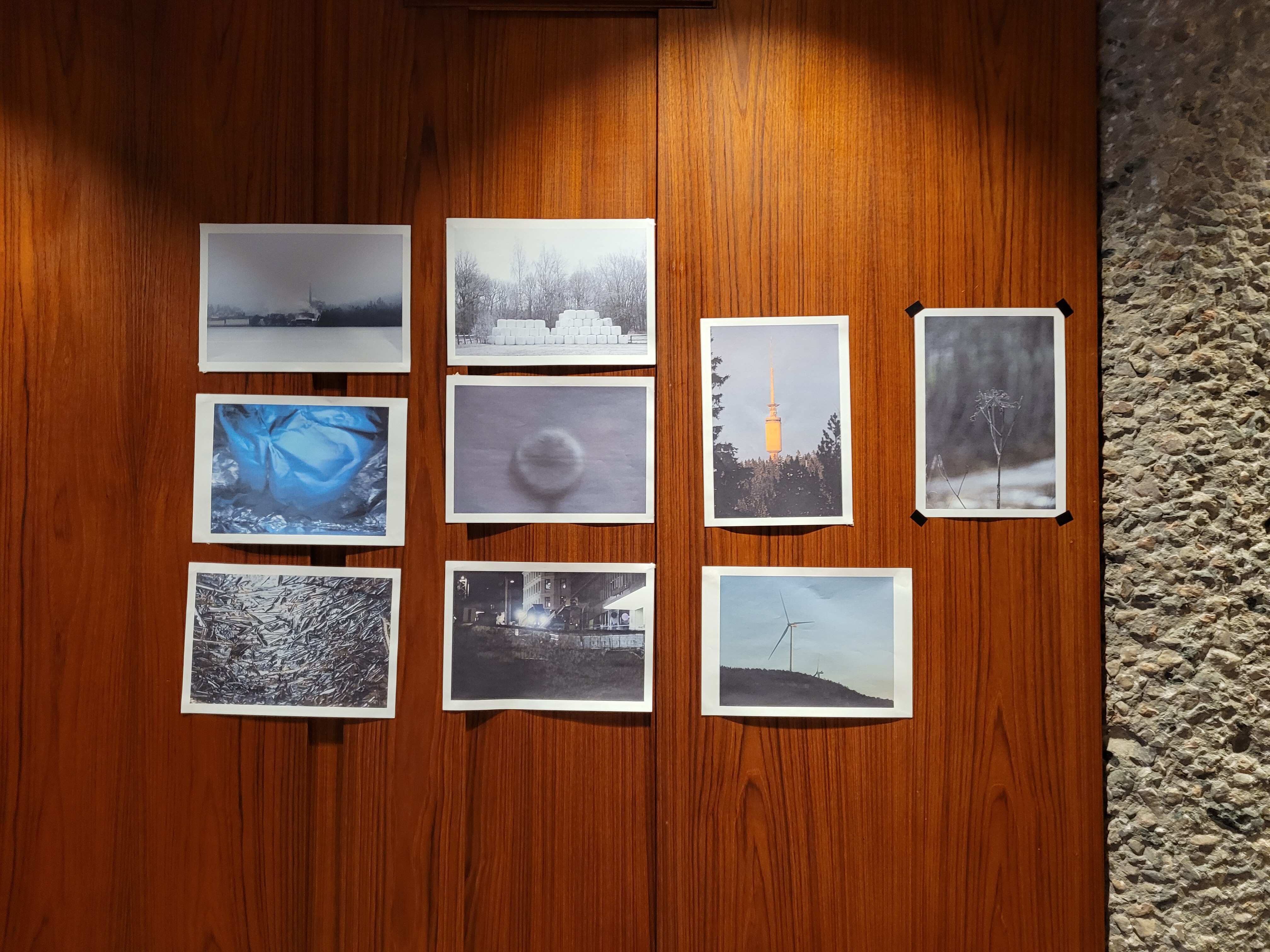 A selection of photos taped to a wooden wall