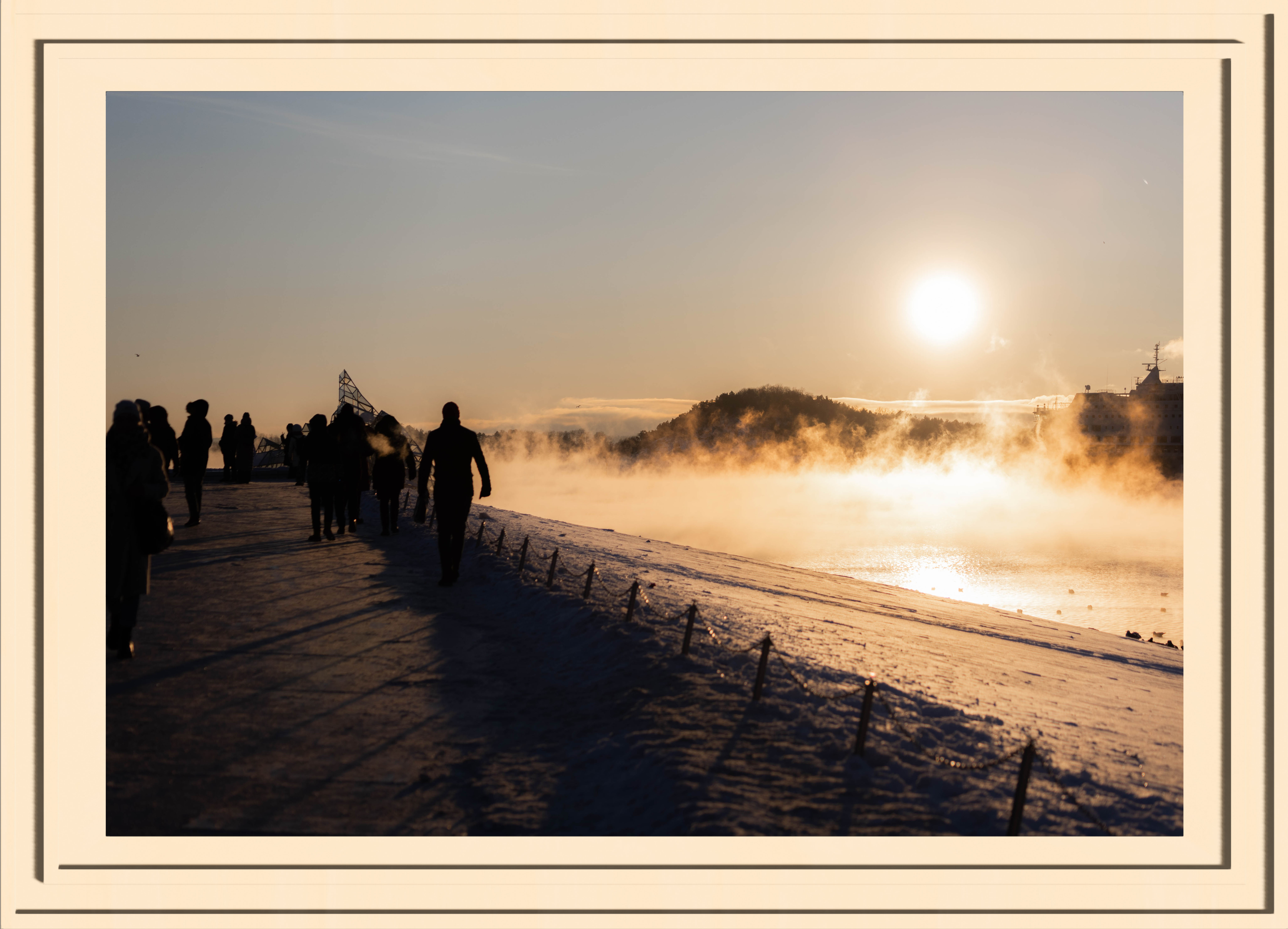 Silhouettes of people nex to steaming water in a golden sunset