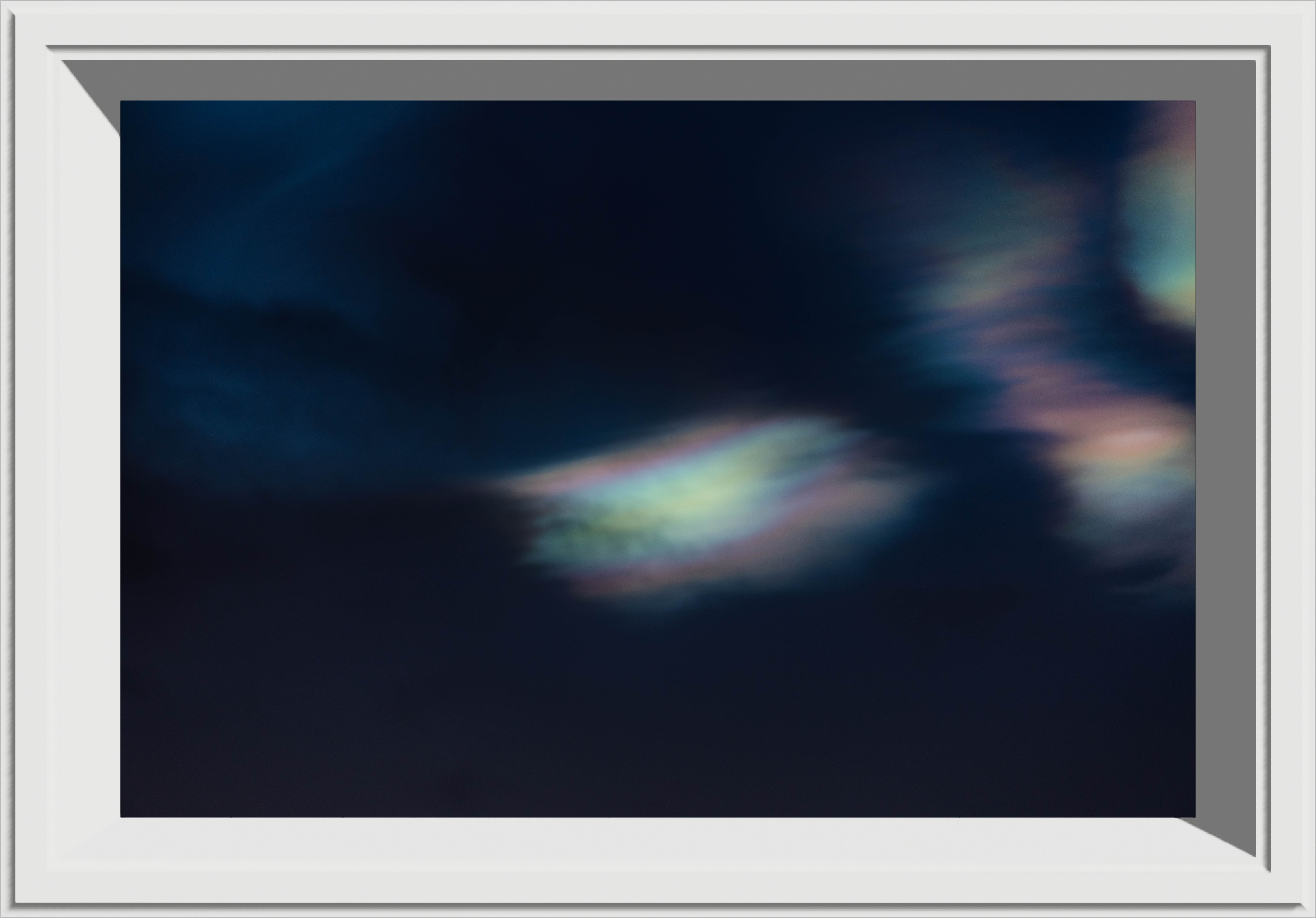 A small rainbow cloud in a dark sky, framed in a thick white frame