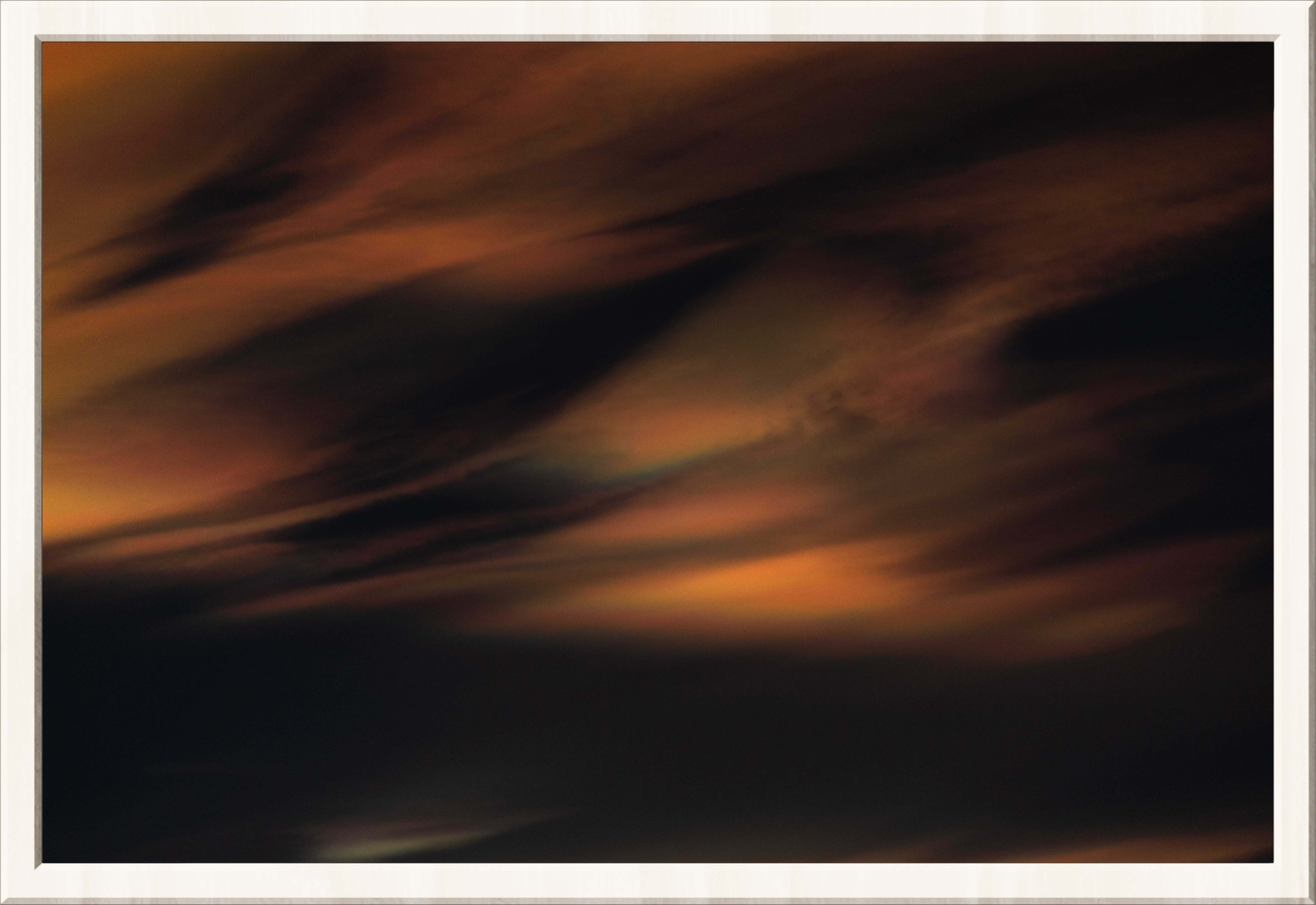 Very orange, wind scattered rainbow clouds in a dark sky