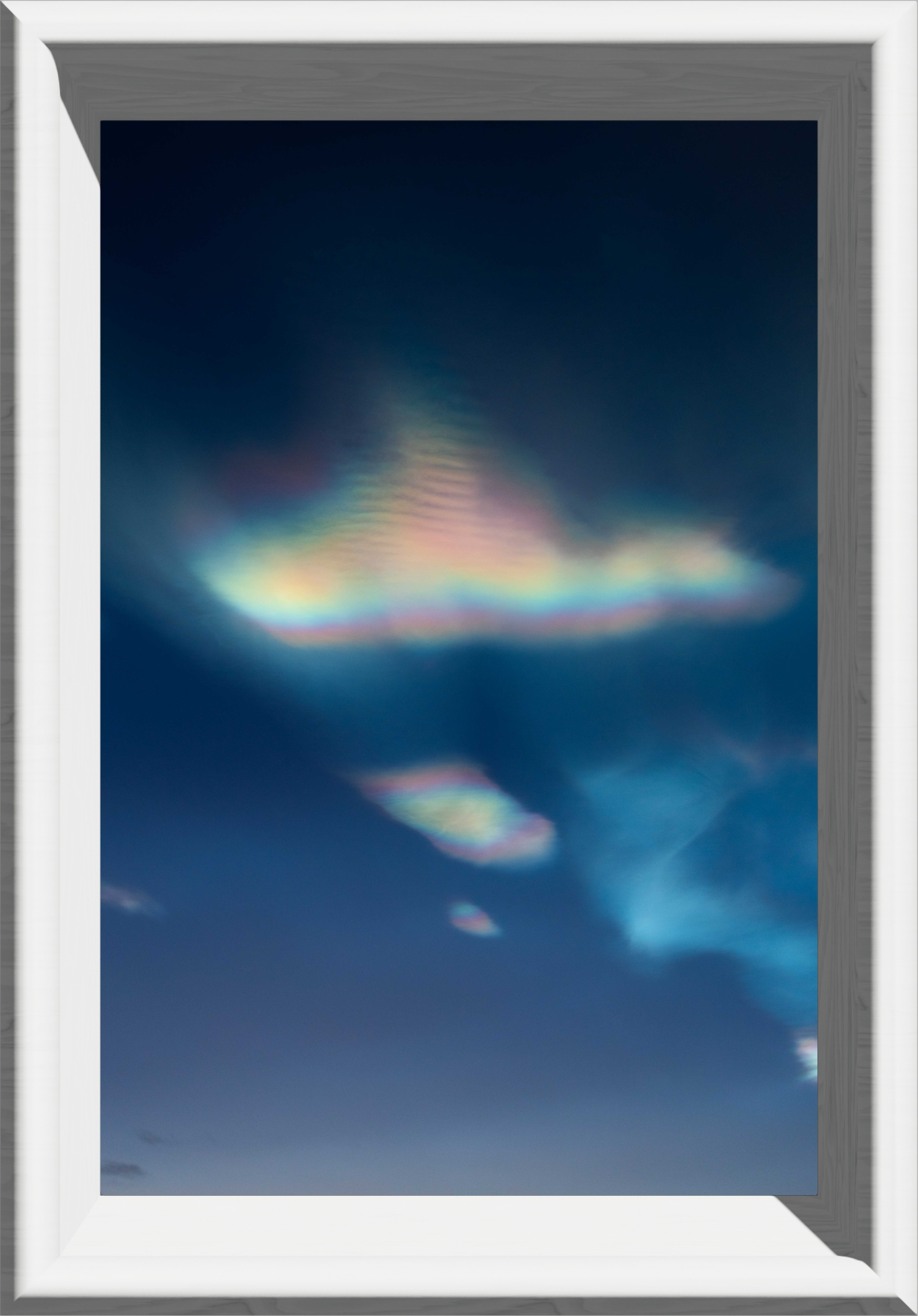 A large, rasinbow, flowy cloud with a smaller clpoud under and another tiny cloud under it, in a white frame